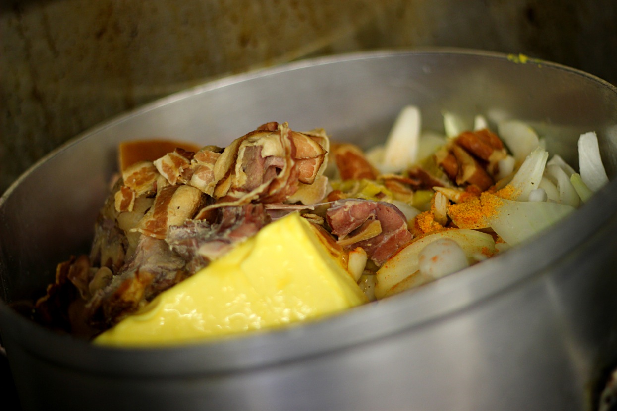 Smoked meat, sliced onions, seasoning and a block of butter going into a stockpot in the Silver Sands kitchen
